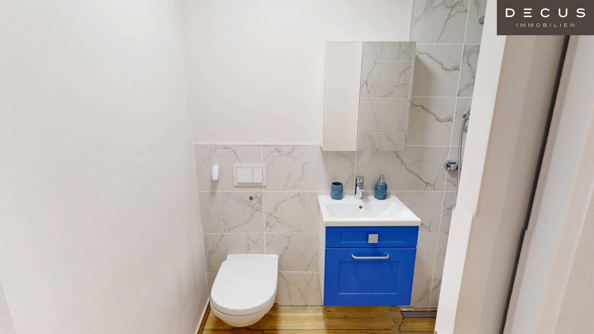 Kleines Gäste-WC mit Wand-WC, Waschbecken und modernen Marmorfliesen.
