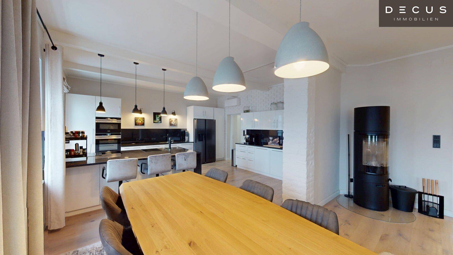 Geräumiger Essbereich mit großem Holztisch und moderner Küche im Hintergrund.