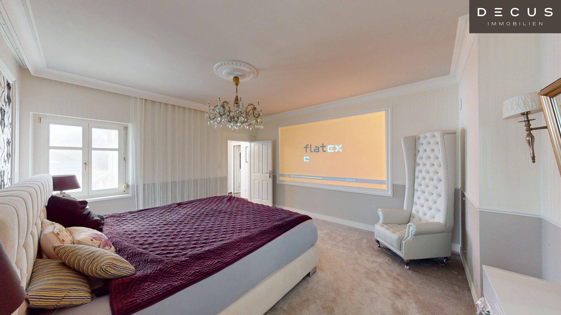Luxuriöses Schlafzimmer mit großem Bett, Kronleuchter und integriertem Projektorbildschirm.