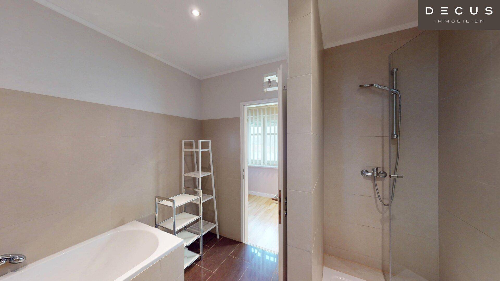 Modernes Badezimmer mit Badewanne, Dusche und hellem Fliesenboden.