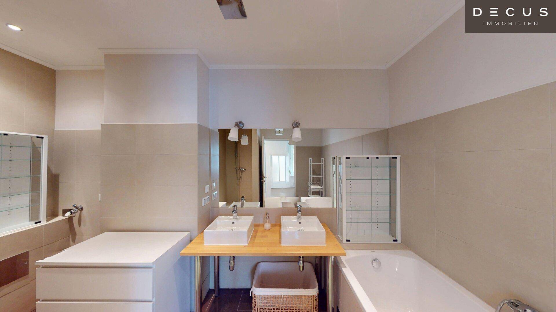 Helles Badezimmer mit Doppelwaschbecken, Badewanne und großer Spiegelfläche.