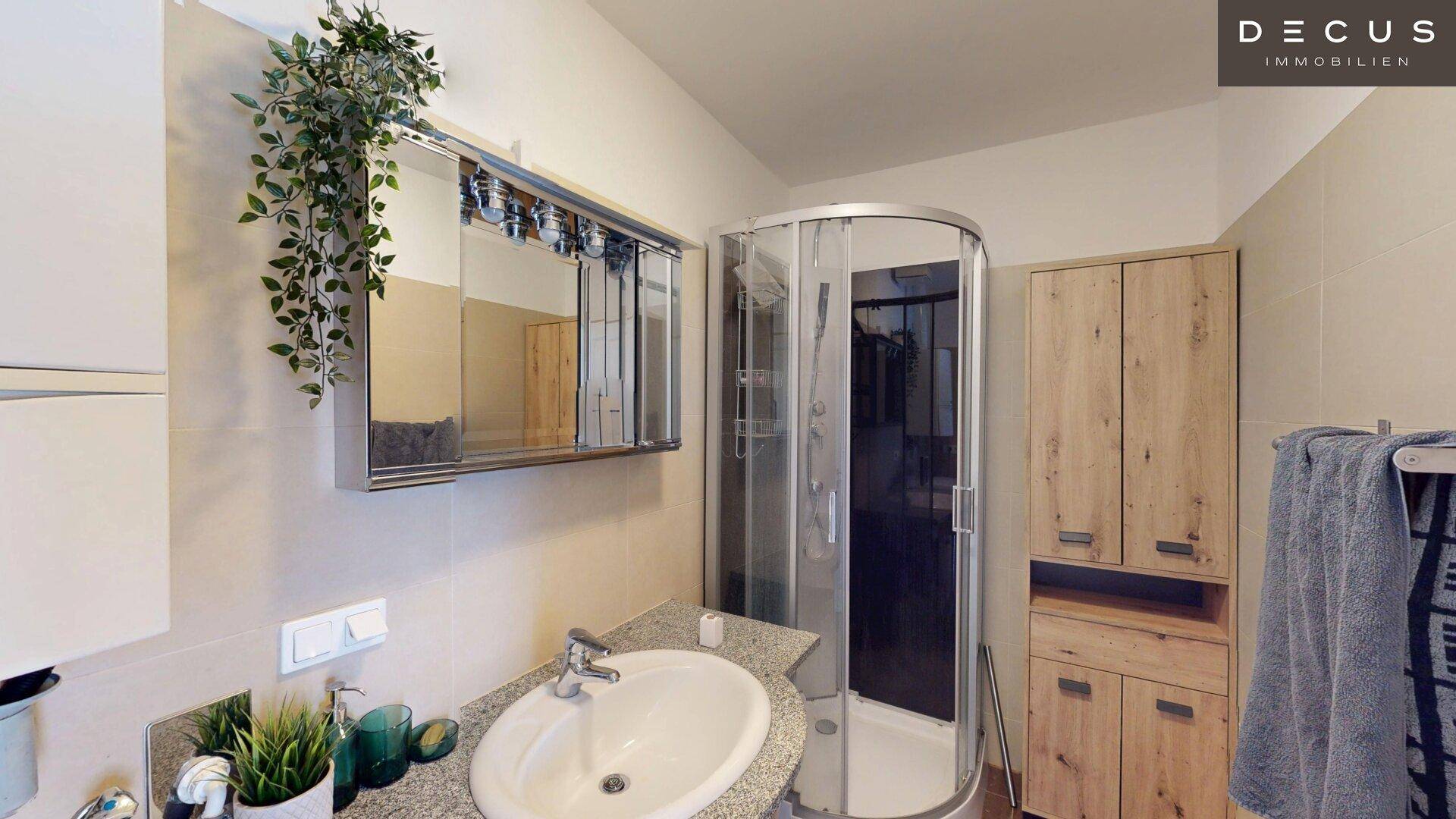 Modernes Badezimmer mit Duschkabine, Einzelwaschbecken und Holzschränken.