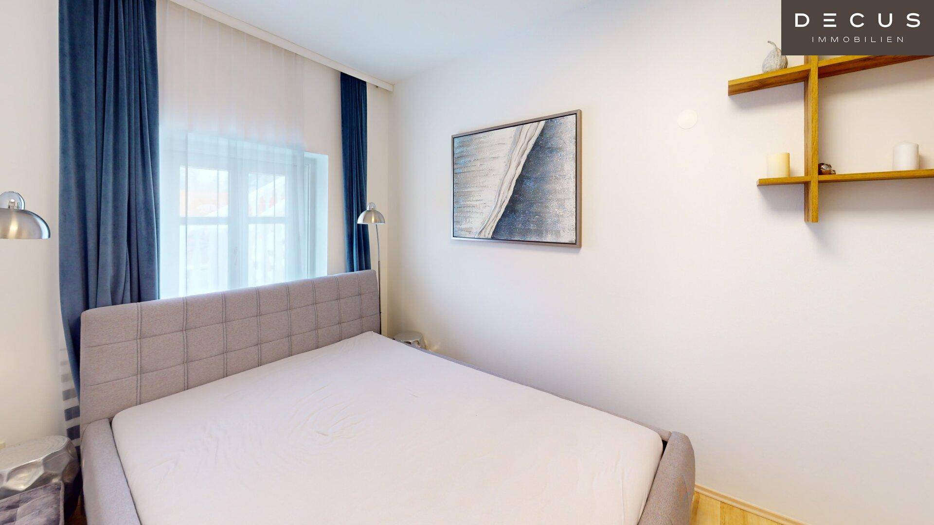 Gemütliches Schlafzimmer mit Doppelbett, blauen Vorhängen und hellem Holzboden.