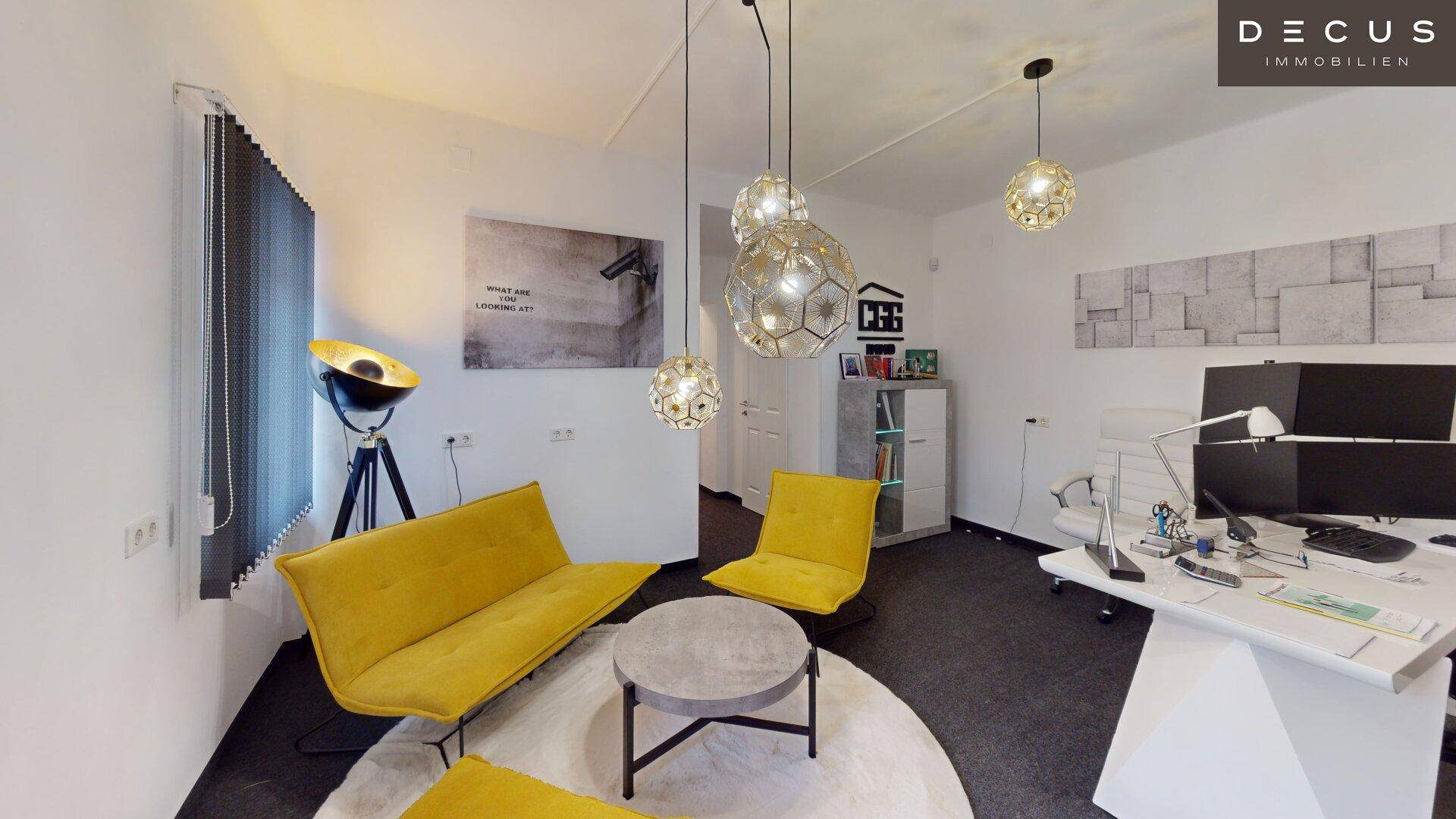 Helles Büro mit gelben Sesseln, Schreibtisch und modernen Pendelleuchten.