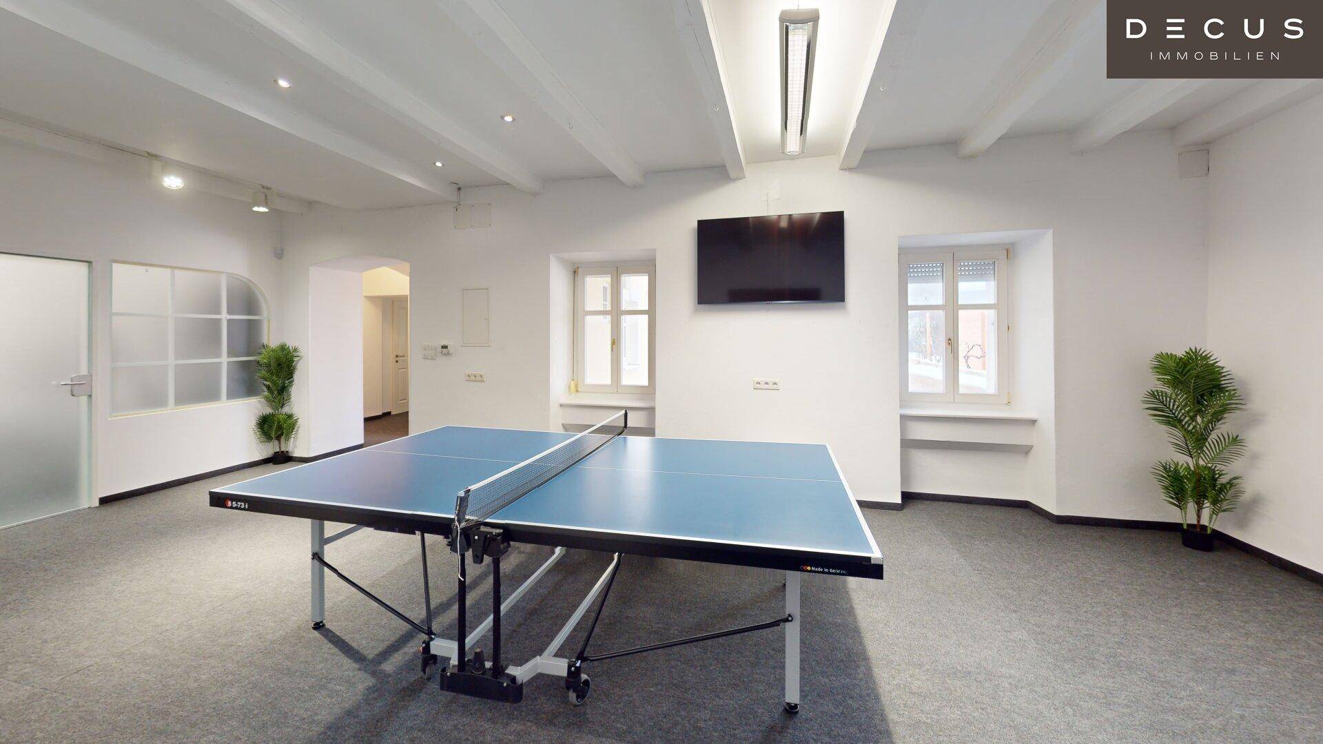 Großer Spielraum mit Tischtennisplatte und Fernseher an der Wand.