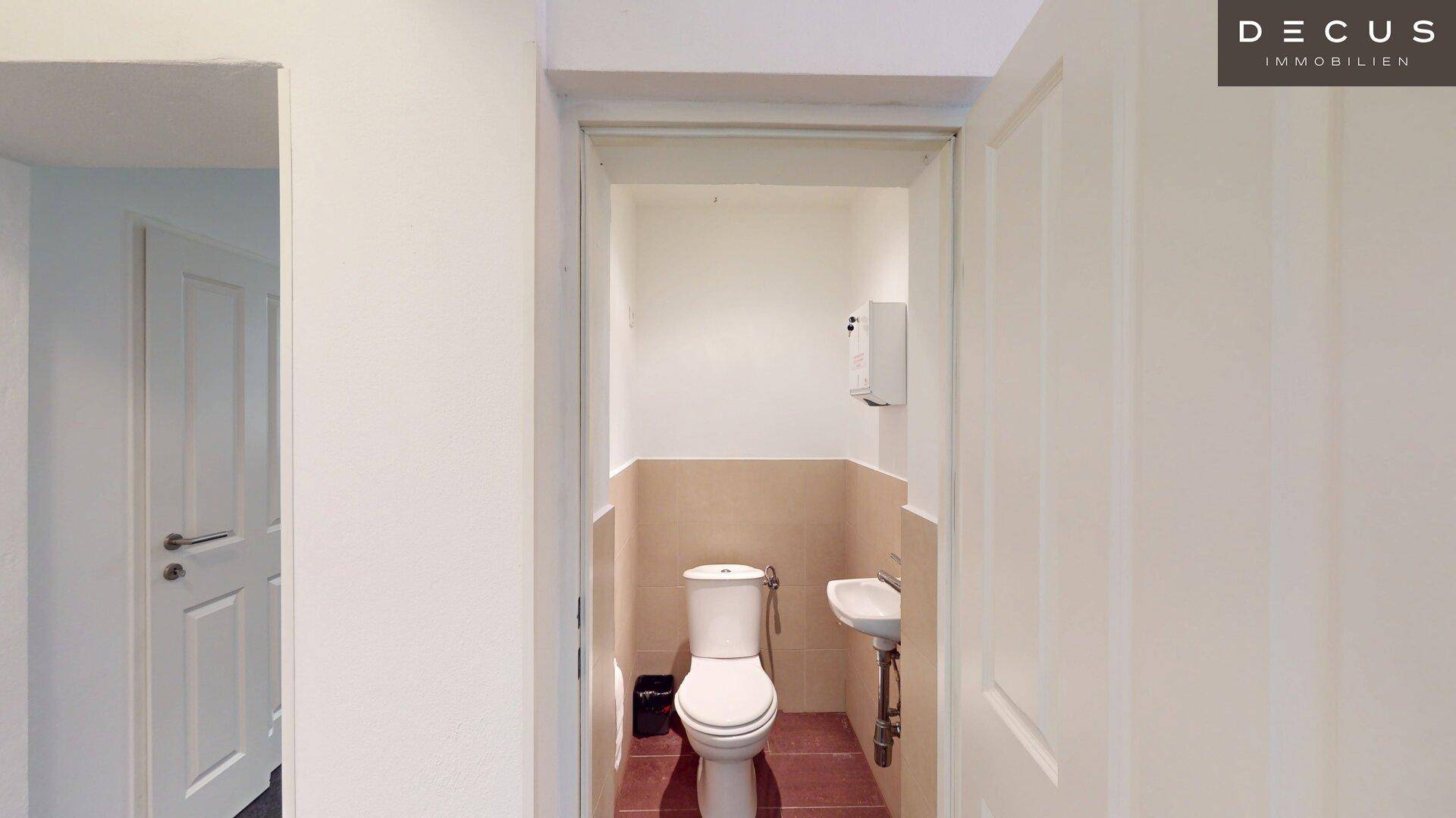 Kleines Gäste-WC mit Toilette und Waschbecken in schlichtem Design.