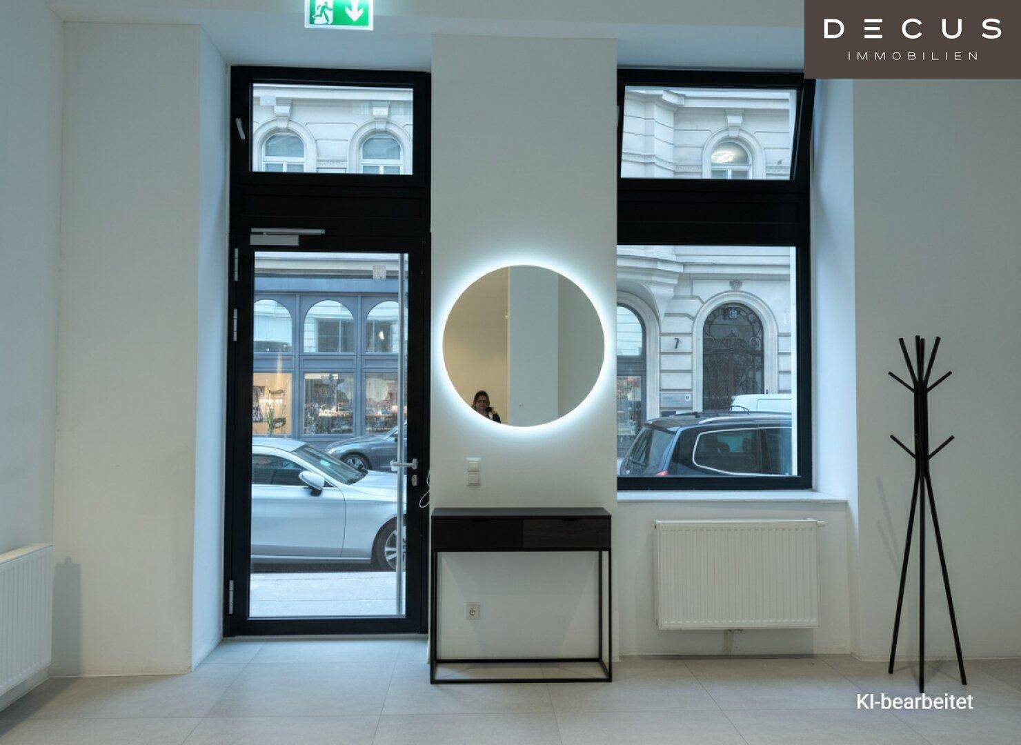 Moderner Eingangsbereich mit beleuchtetem Spiegel, dunklem Konsolentisch und Blick auf die Straße.