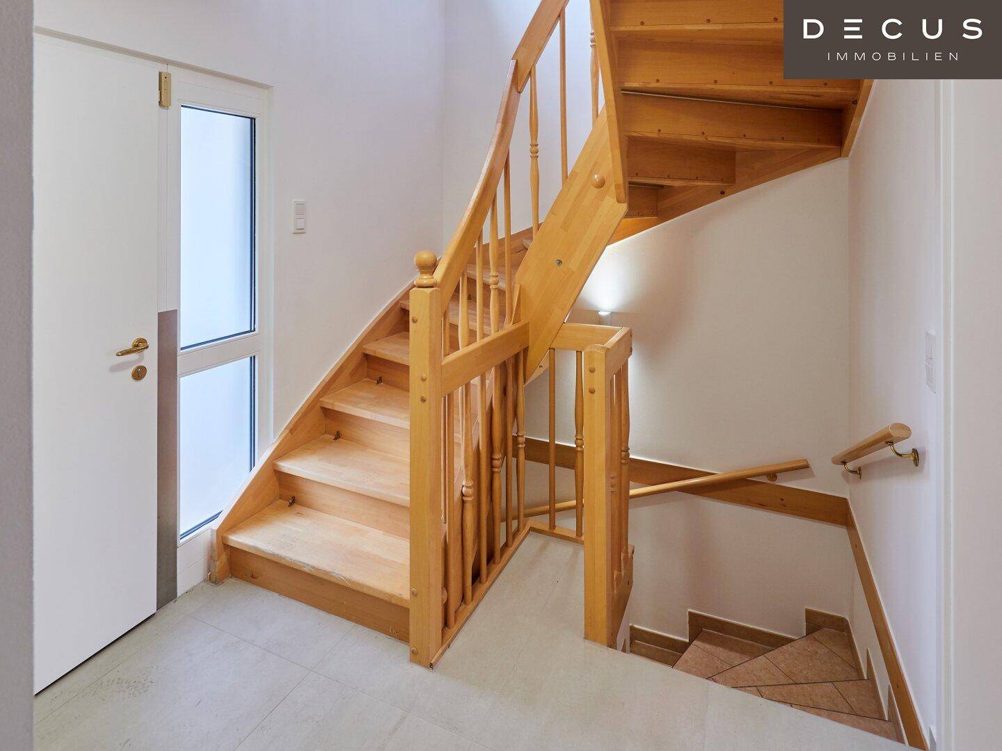Helles Treppenhaus mit Holztreppe und Geländer, das die verschiedenen Etagen verbindet.