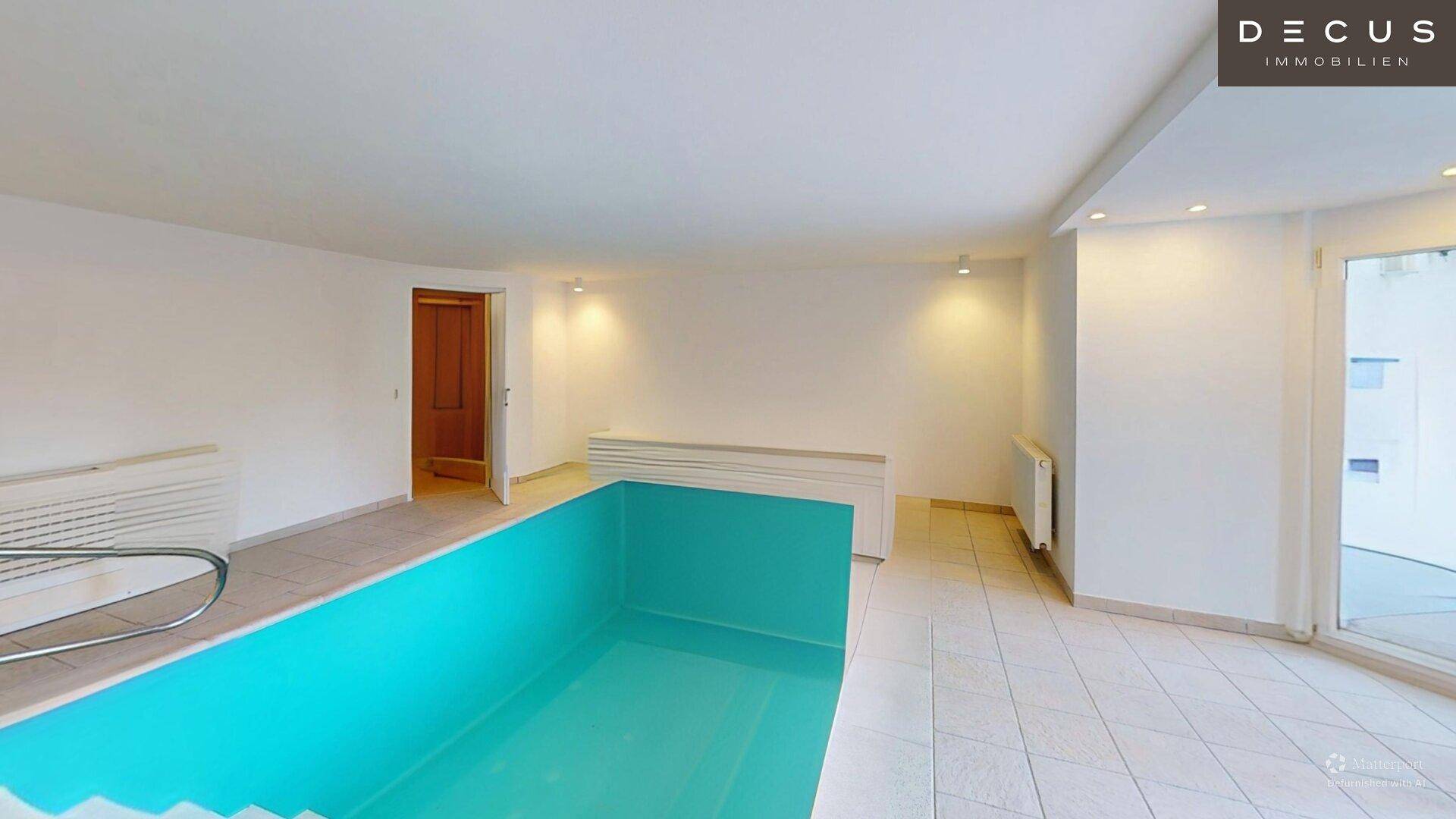 Geräumiger Innenpoolbereich mit Fliesenboden und Treppenzugang zum Schwimmbecken.