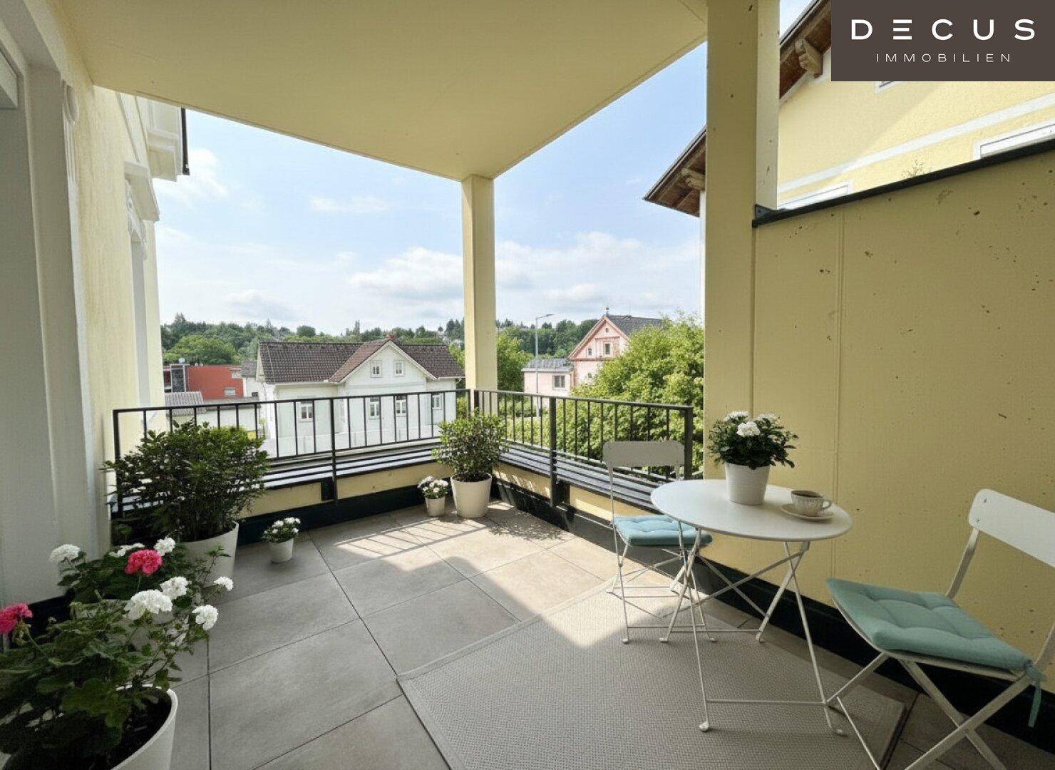Heller Balkon mit Fliesenboden, Sitzgelegenheiten und weitem Blick über die Umgebung.