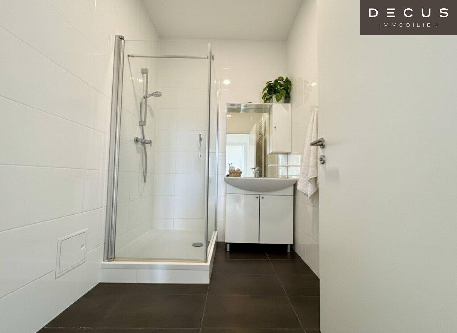 Modernes Badezimmer mit Duschkabine, Waschbecken und weißen Wandfliesen.