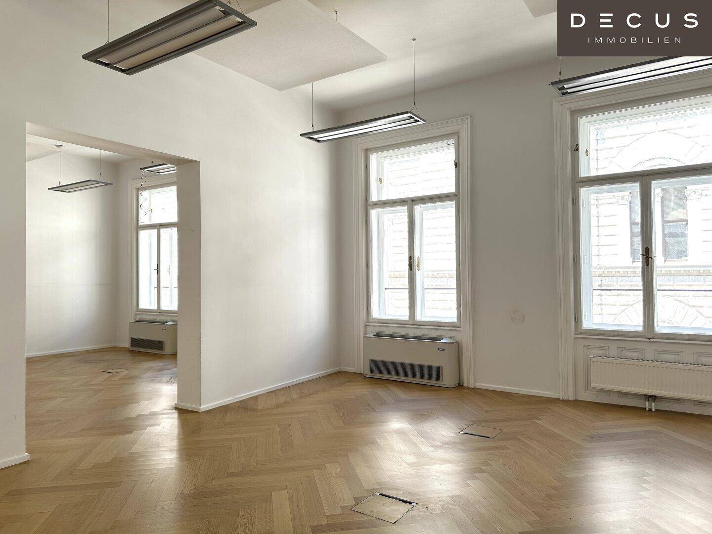 Leeres Büro mit Fischgrätparkett und hohen Fenstern, bereit zur individuellen Gestaltung.