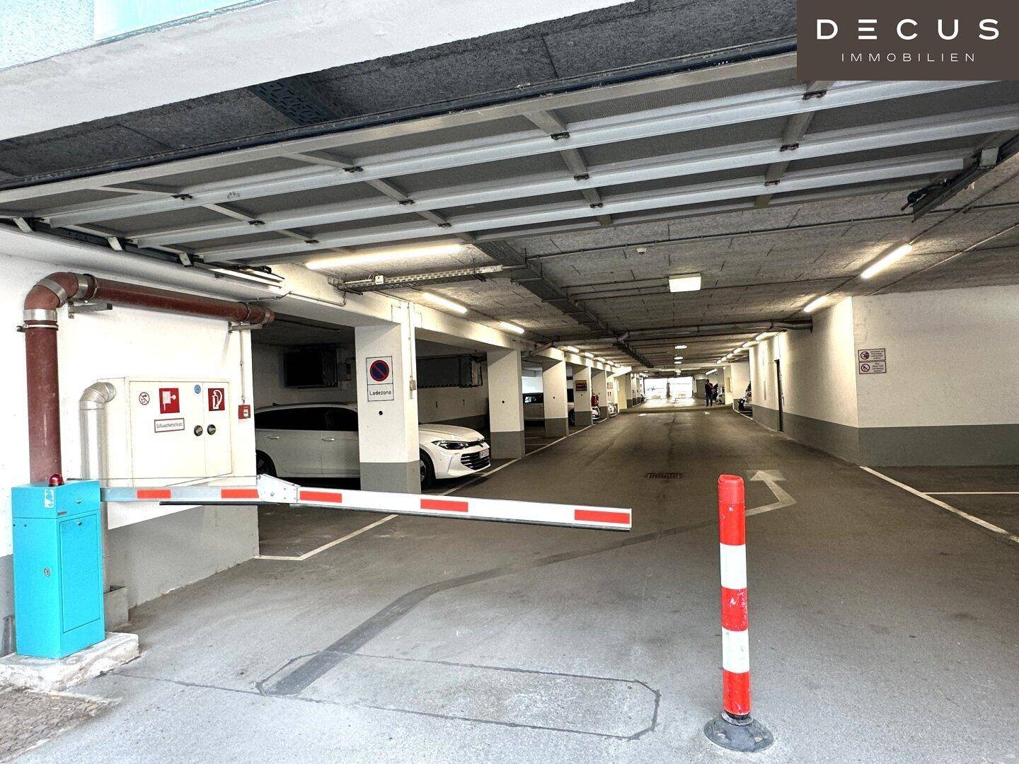 Tiefgarage mit Schranke, Betonwänden und mehreren Parkplätzen für Fahrzeuge.