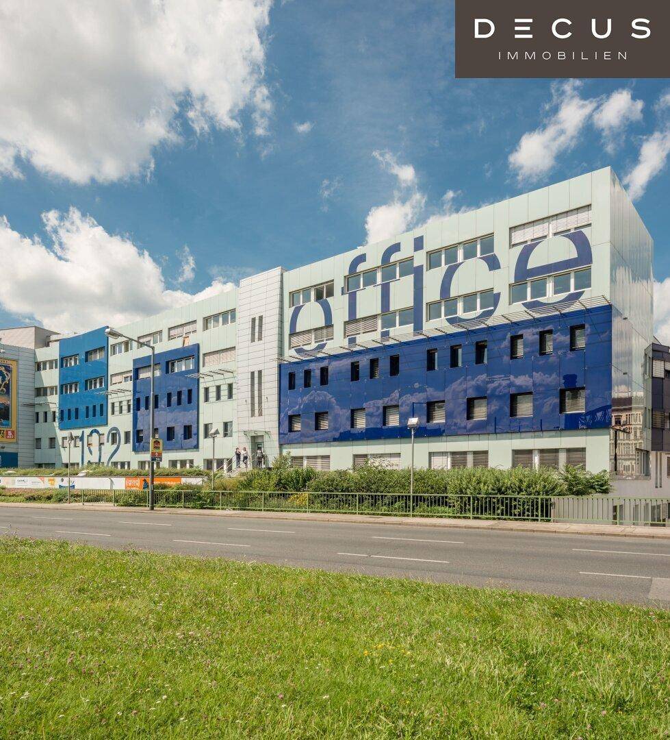 Modernes Bürogebäude mit auffälliger blauer und weißer Fassade sowie Schriftzug an einer Straße.