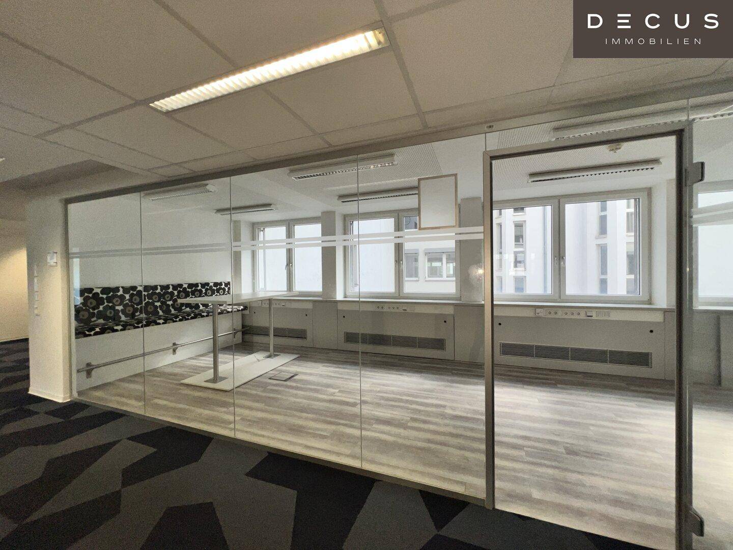 Großes Büro mit Glaswänden, die eine offene Atmosphäre schaffen und viel Licht hereinlassen.