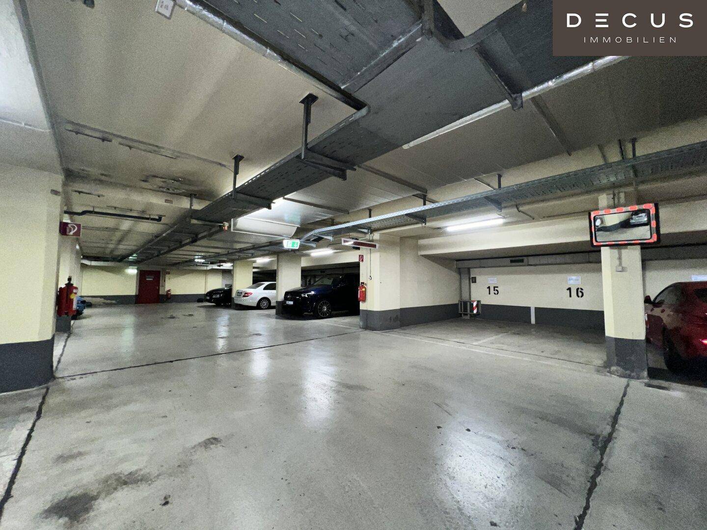 Geräumige Tiefgarage mit mehreren Parkplätzen und sichtbaren Installationen an der Decke.