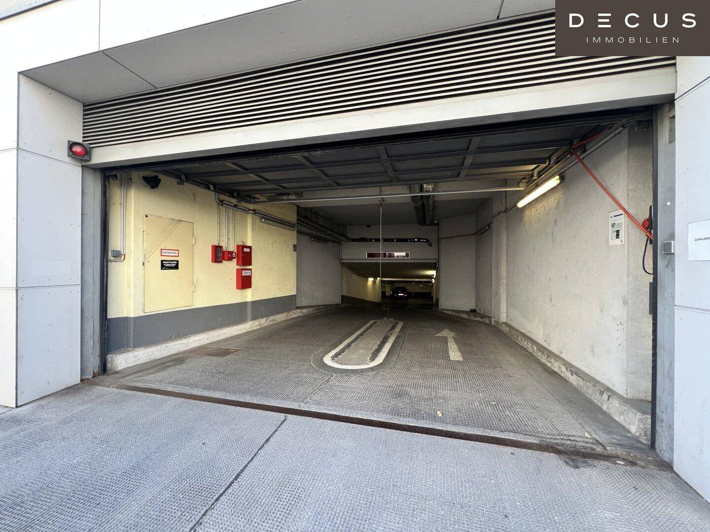 Eingangsbereich einer Tiefgarage mit Rolltor und Hinweisschildern, gut zugänglich und sicher.