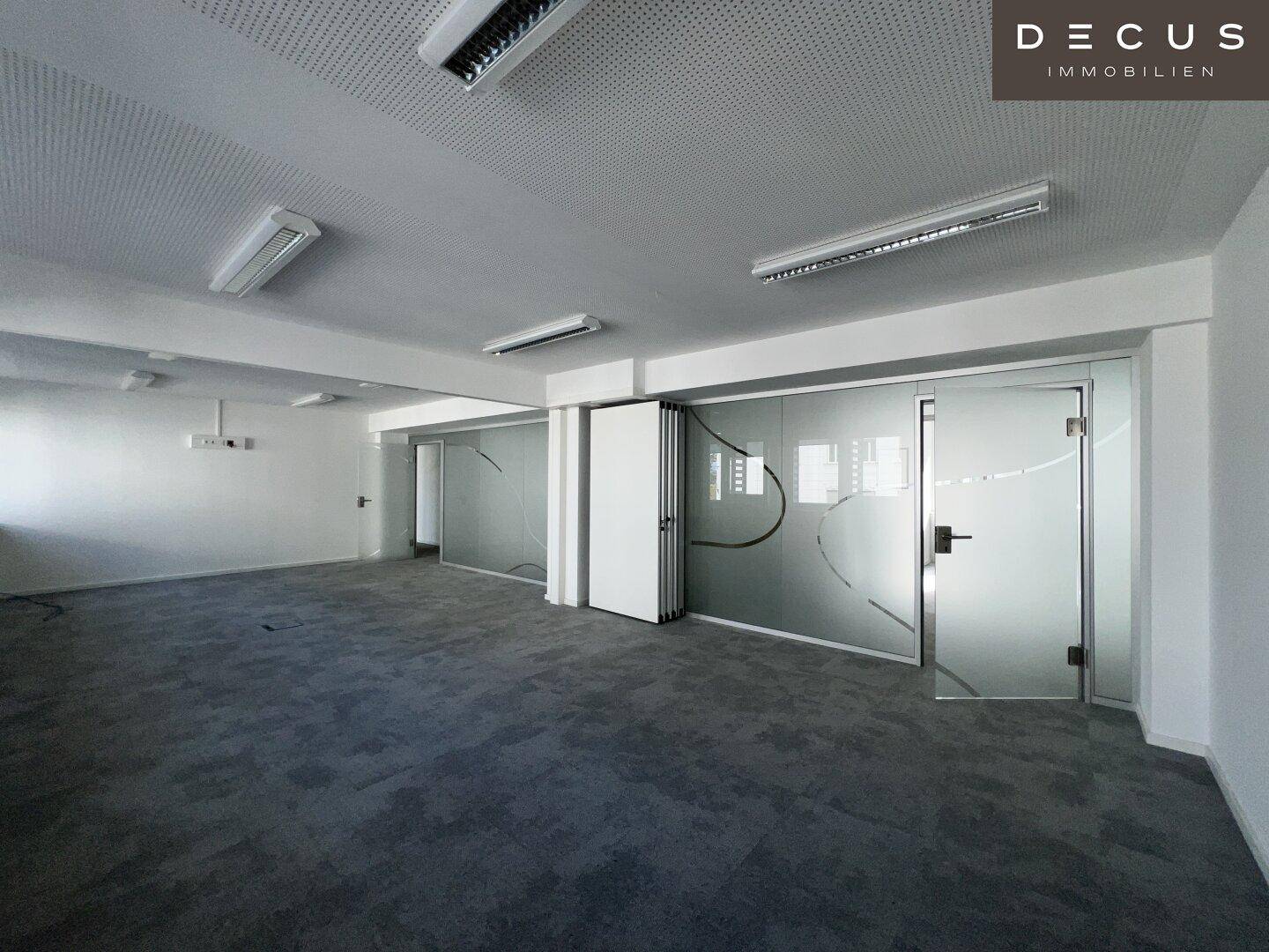 Helles Büro mit flexiblen Glaswänden und Türen, ideal für eine moderne Arbeitsumgebung.