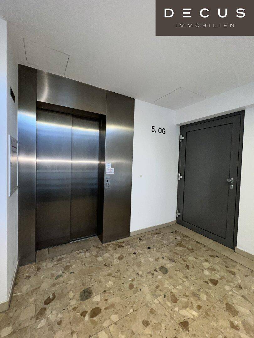 Moderner Aufzugsbereich mit Edelstahltüren und Terrazzoboden im fünften Obergeschoss.
