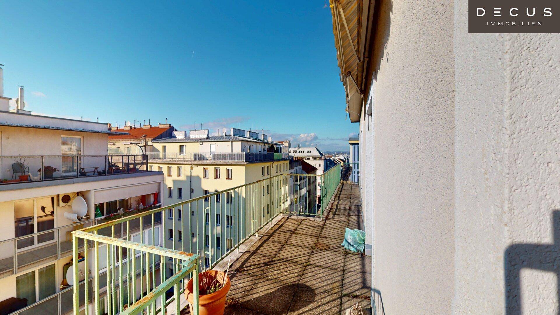 Langer Balkon mit Metallgeländer und Blick auf die umliegenden Wohngebäude.