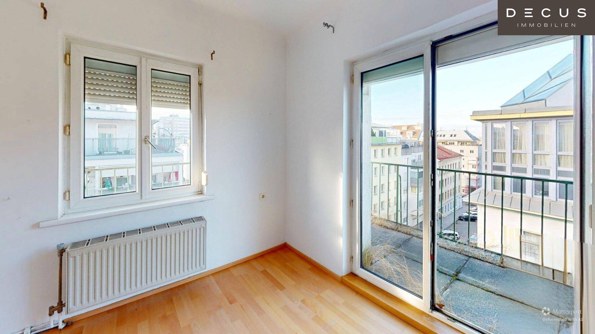 Lichtdurchfluteter Raum mit Parkettboden und direktem Zugang zu einem Balkon mit Stadtblick.