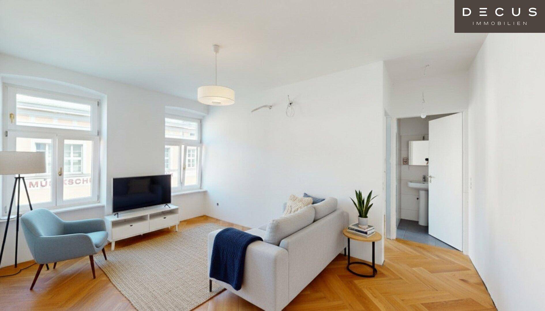 Modern eingerichtetes Wohnzimmer mit Sofa, Fernseher und Blick auf das Badezimmer.