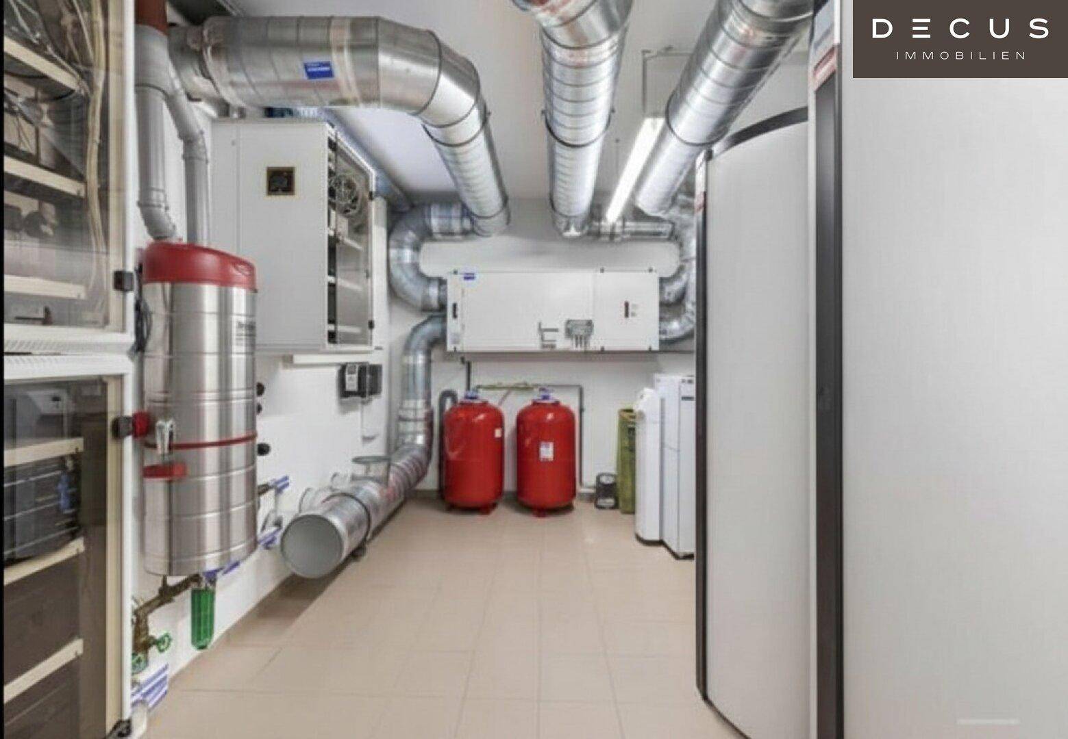 Technischer Raum mit umfangreichen Lüftungsrohren und Heizungsanlagen im Kellerbereich.