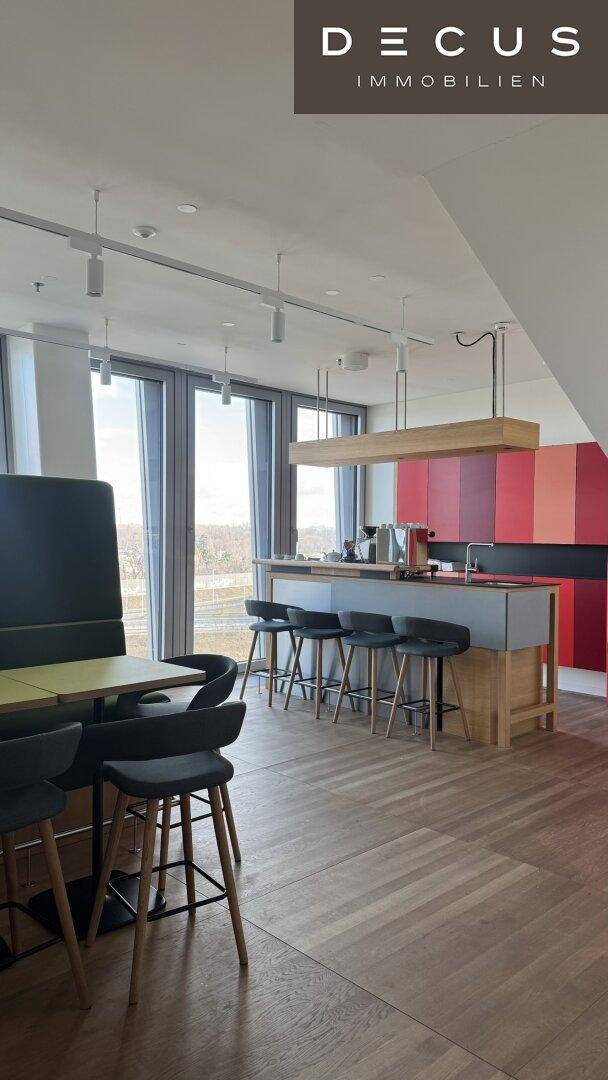 Moderne Küchenzeile mit Barhockern und Holzboden, integriert in einen offenen Lounge-Bereich.