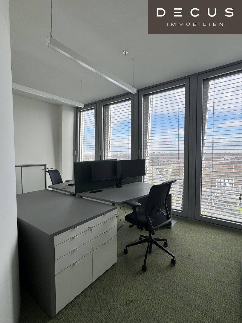 Einzelner Arbeitsplatz mit Schreibtisch, Bürostuhl und großen Fenstern mit weitem Ausblick.