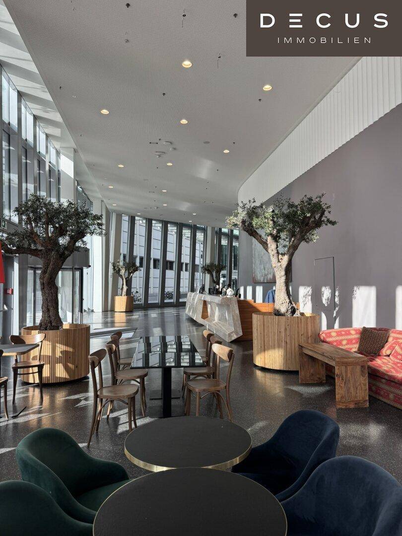 Geräumiger Loungebereich in einer modernen Lobby mit verschiedenen Sitzgelegenheiten und Pflanzen.