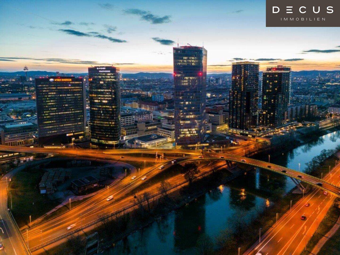 Atemberaubende Luftaufnahme einer modernen Stadtlandschaft bei Sonnenuntergang mit beleuchteten Gebäuden und Brücken.