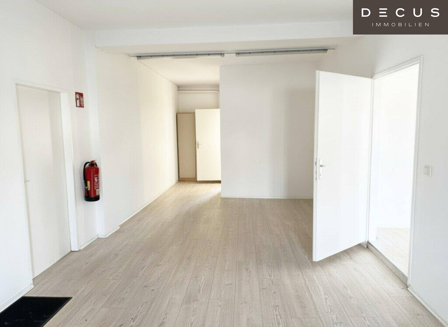 Leerer, heller Raum mit Laminatboden und weißen Wänden, bereit zur individuellen Gestaltung.