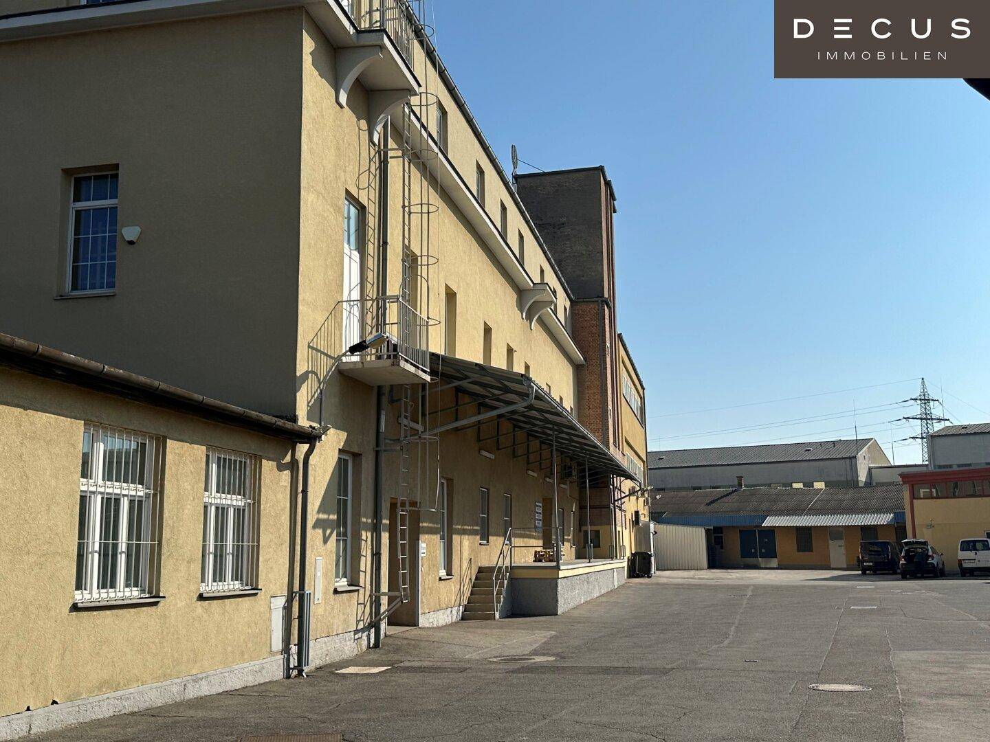 Seitenansicht des Gewerbegebäudes mit langer Fassade, Laderampe und weitem Blick auf das Gelände.