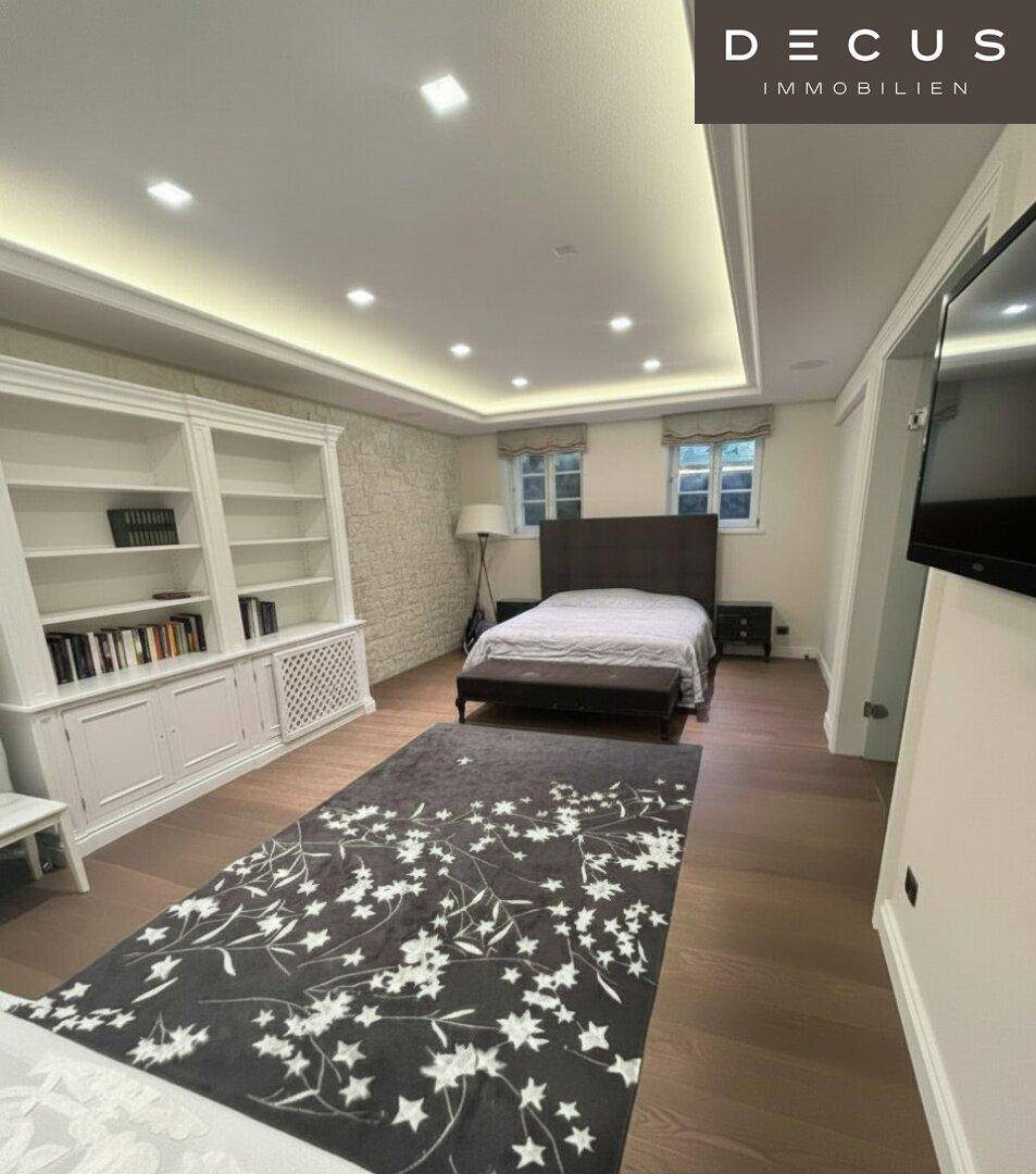 Gemütliches Schlafzimmer mit Holzboden, Einbauregal und indirekter Deckenbeleuchtung.