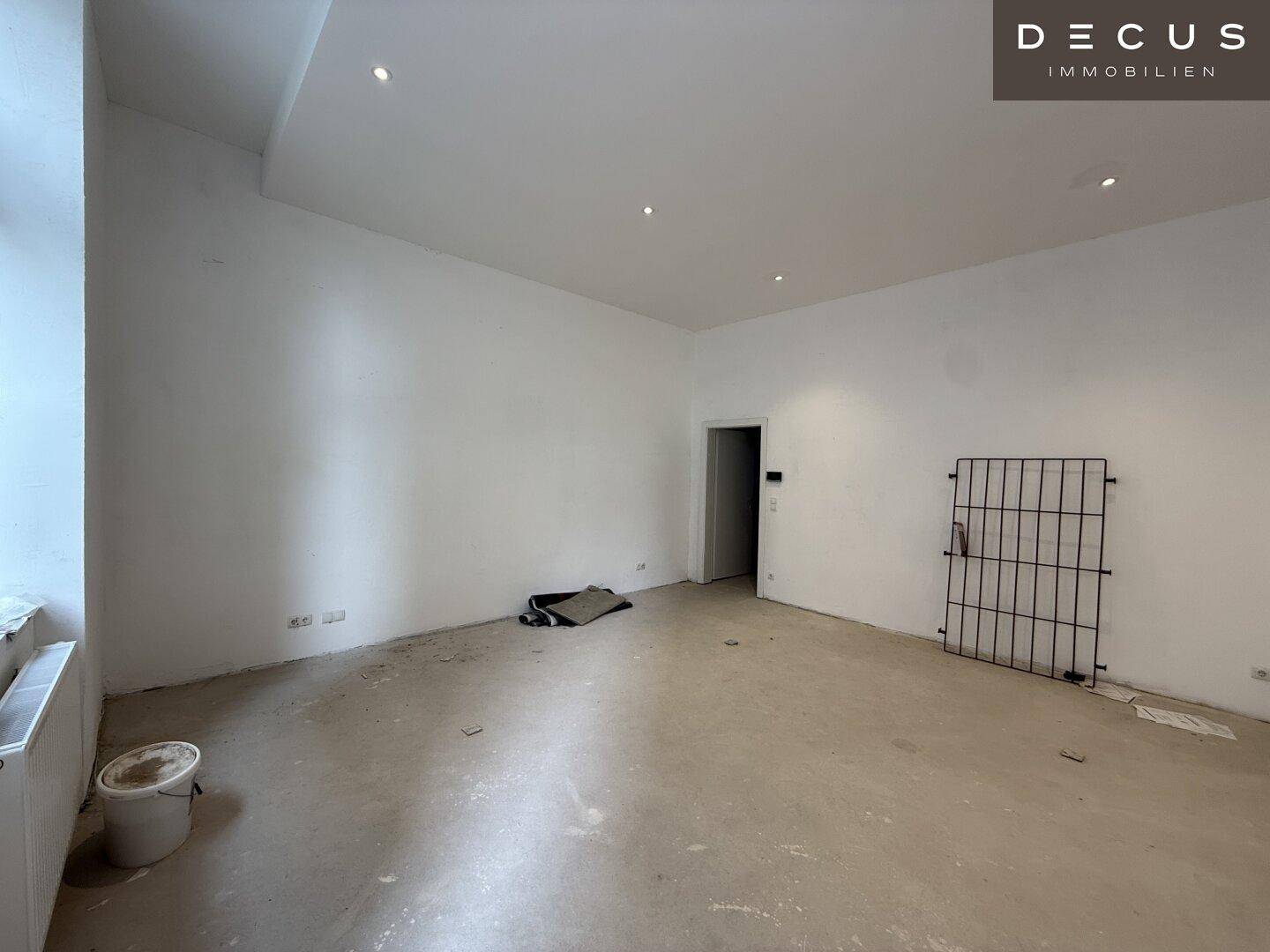 Heller Gewerberaum mit Betonboden, weißen Wänden und Heizkörper, ideal für individuelle Gestaltung.