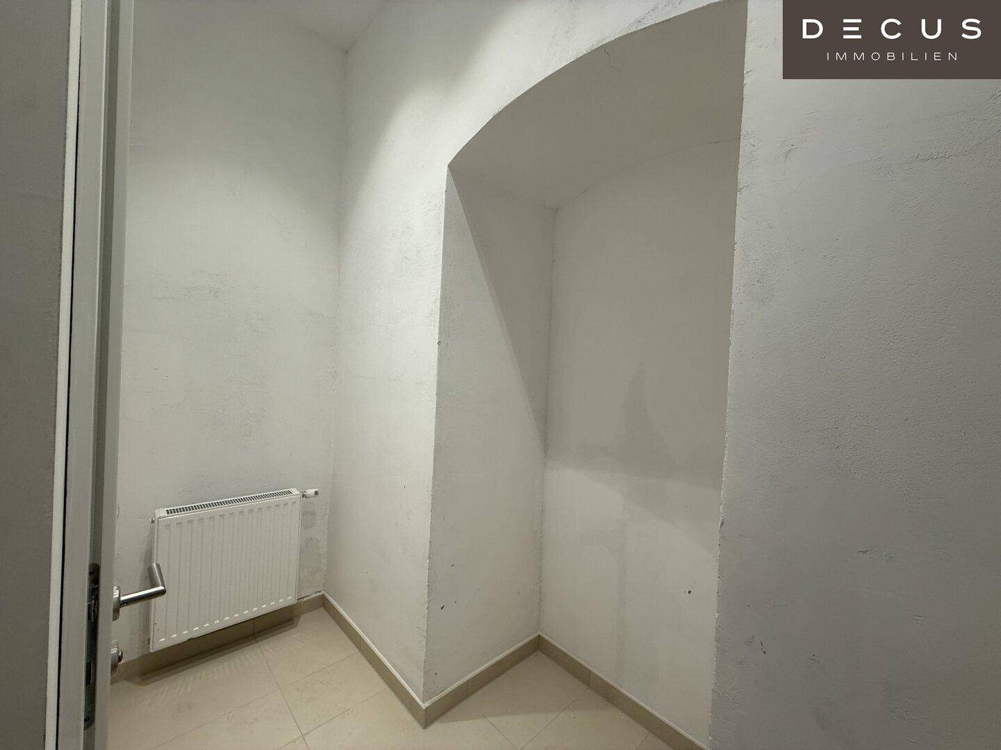 Nische in einer modernen Gästetoilette mit Heizkörper und hellen Fliesen, bietet Stauraum oder Dekorationsmöglichkeiten.