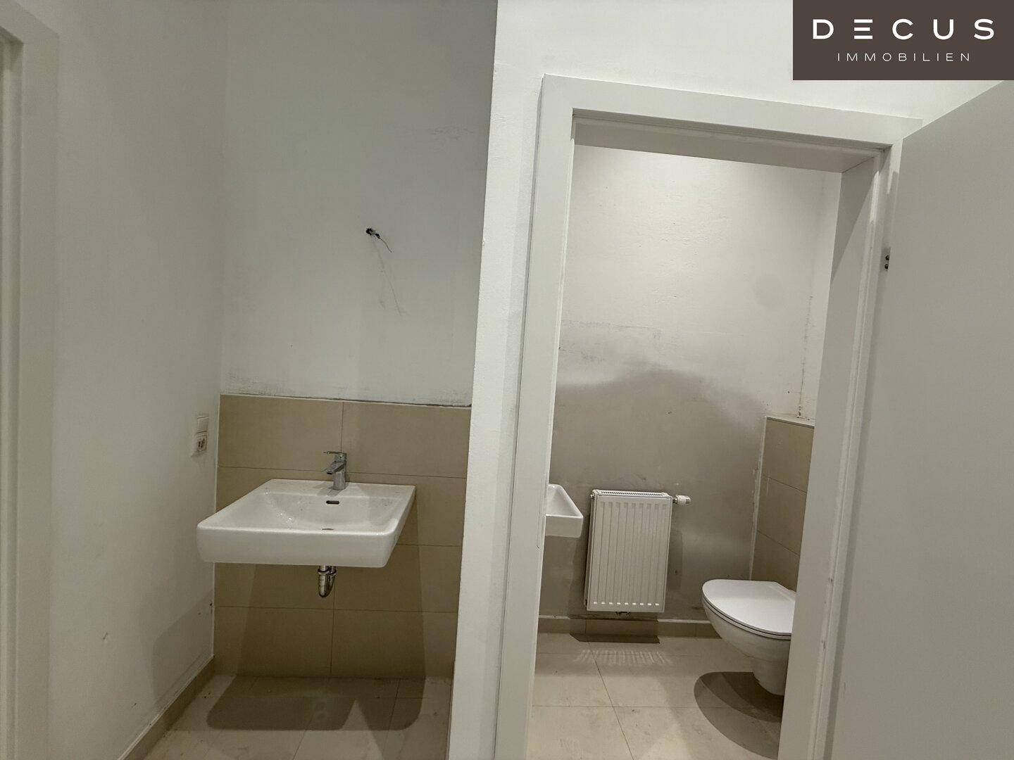 Moderne Gästetoilette mit Waschbecken, wandhängendem WC und hellen Fliesen, in einem gepflegten Zustand.