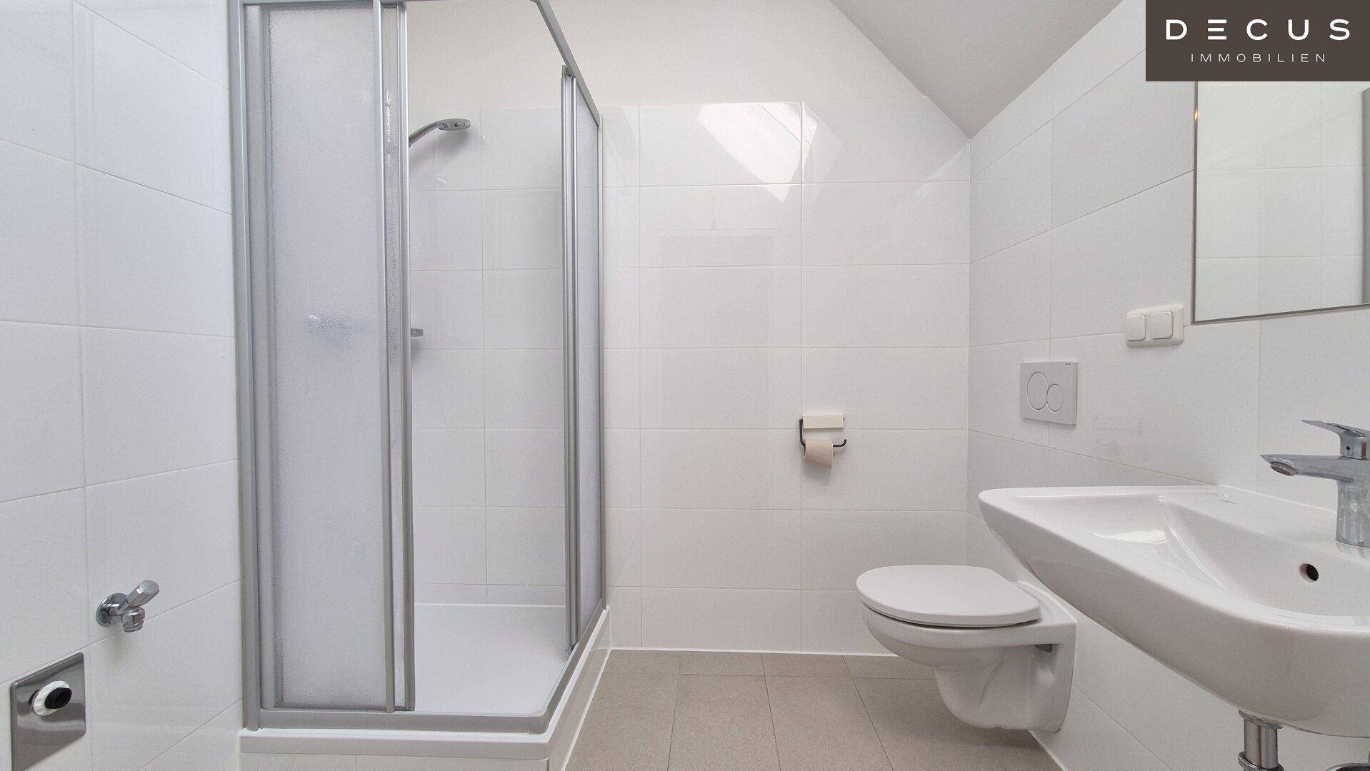 Modernes Badezimmer mit Duschkabine, wandhängendem WC und Waschbecken.