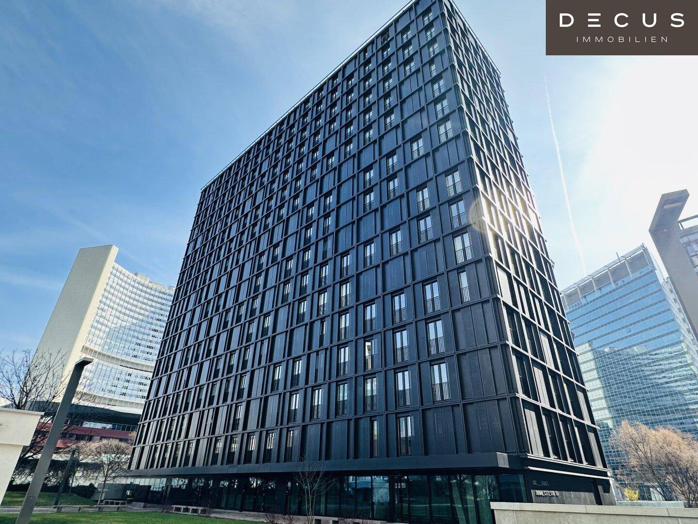 Hohes, modernes Gebäude mit dunkler Fassade und vielen Fenstern unter einem klaren blauen Himmel.