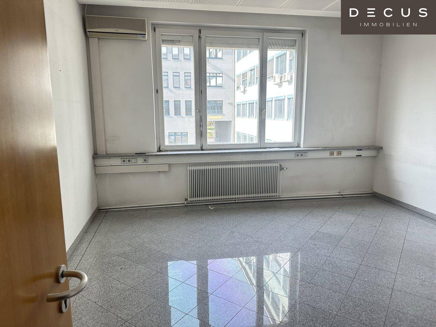 Leeres Büro mit großen Fenstern, Klimaanlage und glänzendem Granitboden, bereit zur Einrichtung.