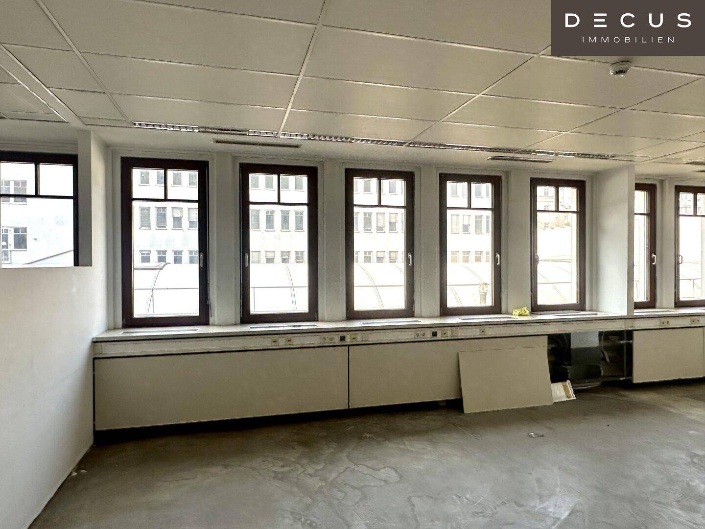 Detailansicht der Fensterfront mit Blick auf umliegende Gebäude und die Installationsleiste darunter.