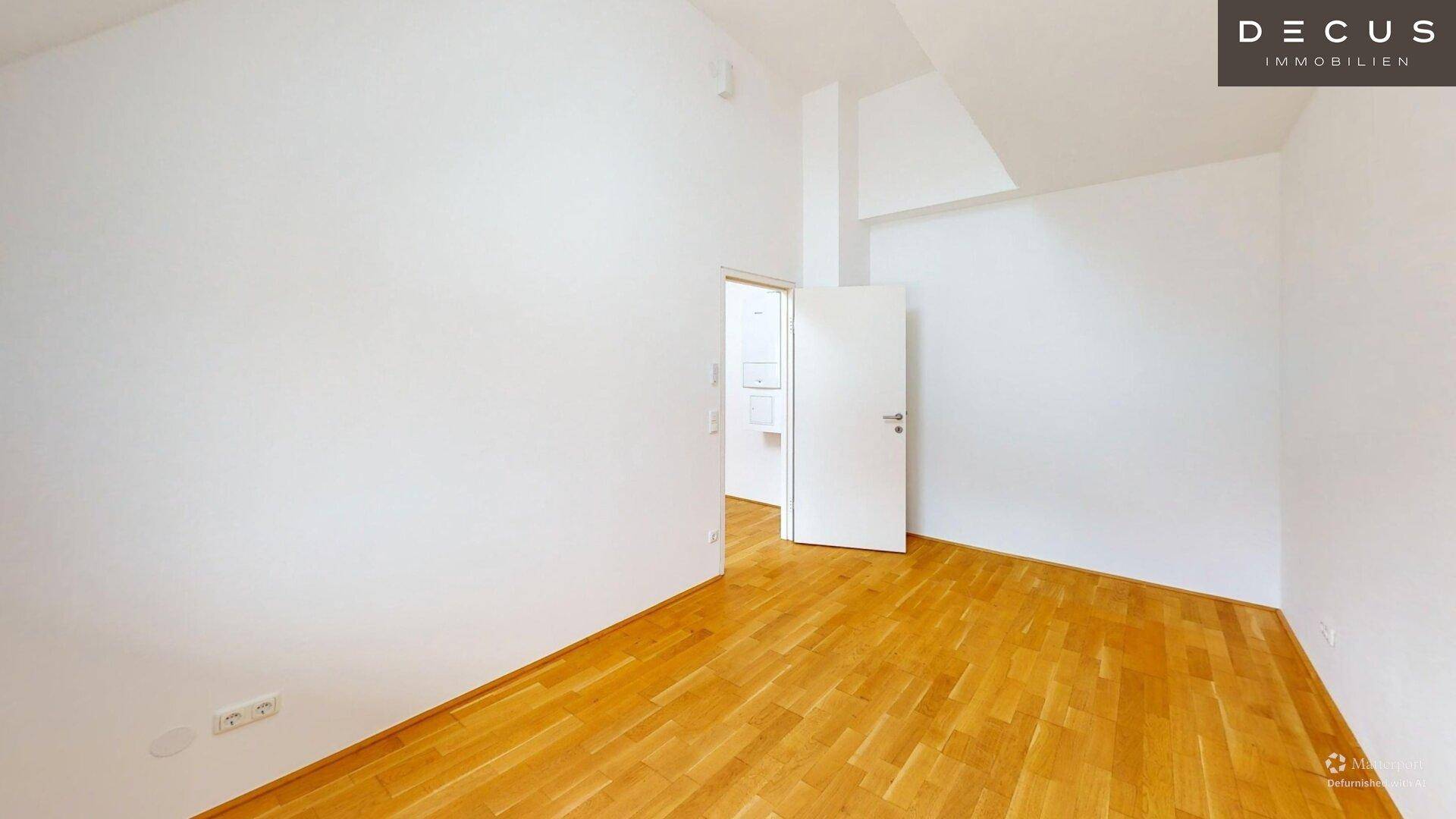 Leeres Zimmer mit Holzboden und weiß gestrichenen Wänden, bereit zur individuellen Gestaltung.