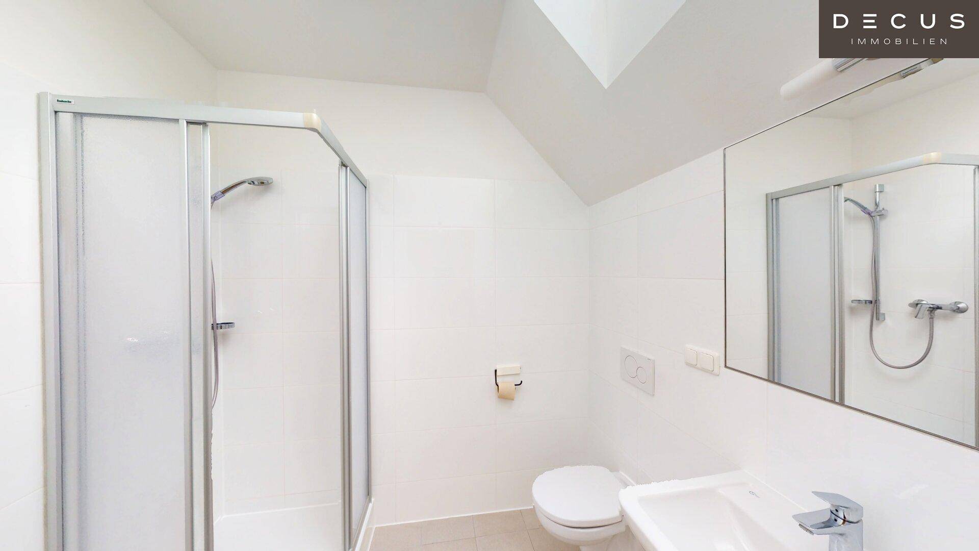 Helles Badezimmer mit Duschkabine, WC, Waschbecken und großem Spiegel.