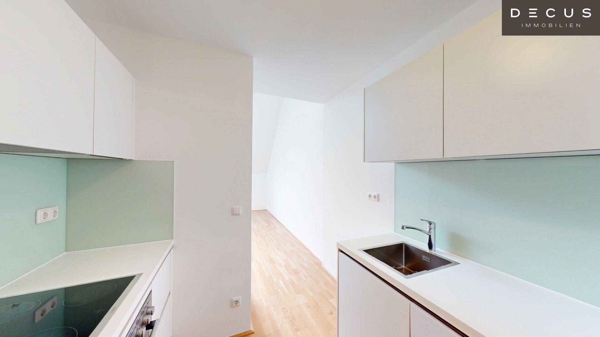 Moderne Einbauküche mit weißen Schränken, heller Arbeitsplatte und integriertem Kochfeld.