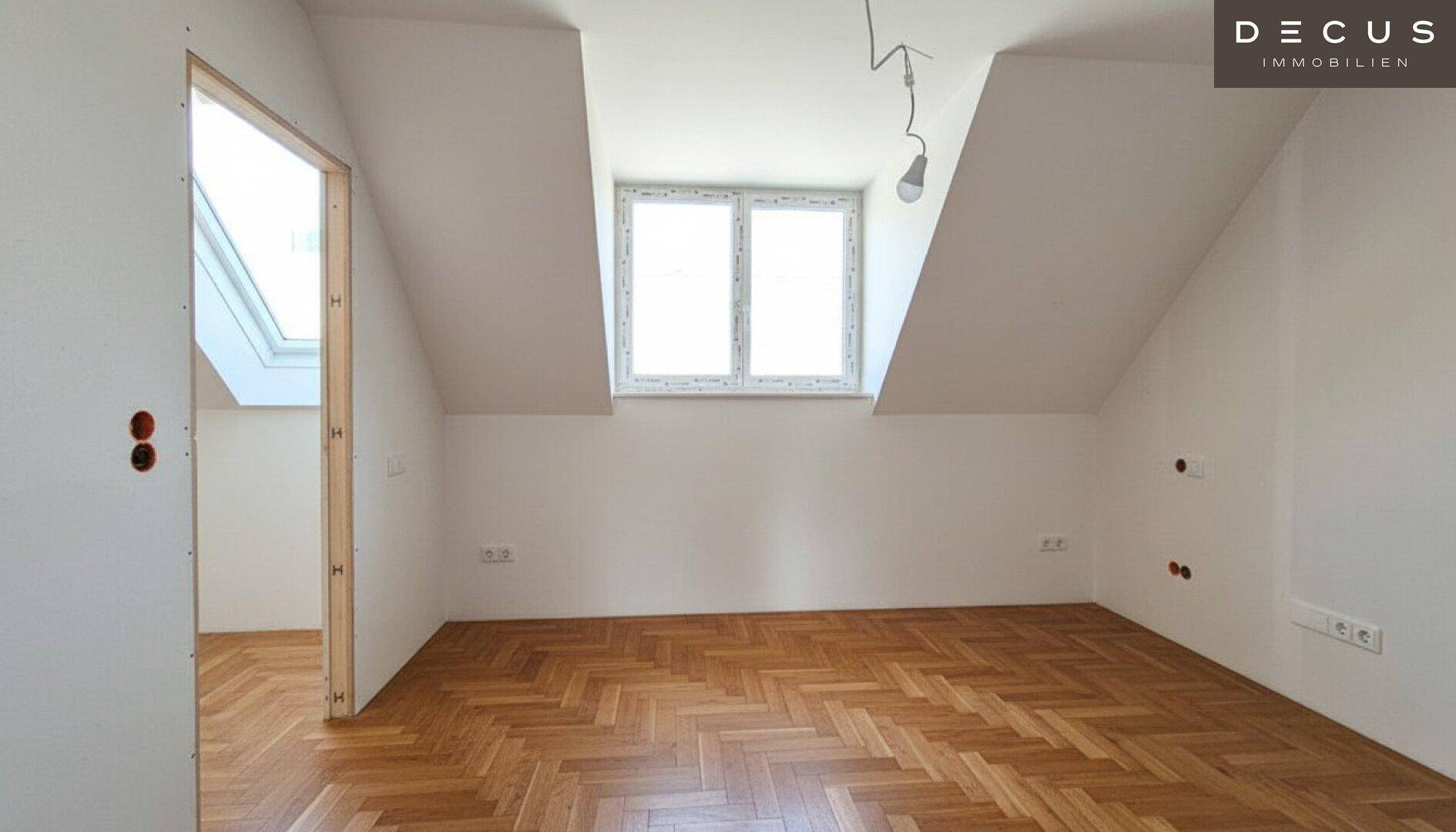 Dachgeschosszimmer mit schrägen Wänden, Dachfenster und Fischgrätparkett, bereit zur Einrichtung.