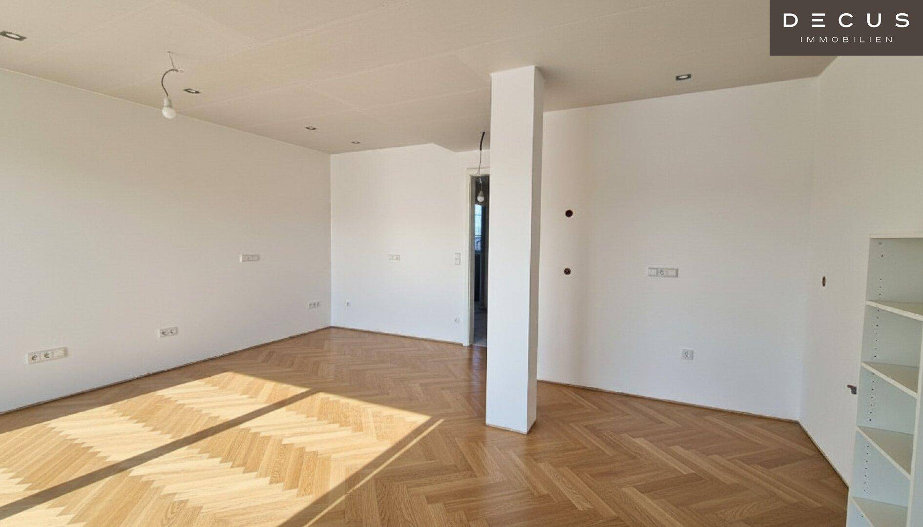 Geräumiger, heller Wohnbereich mit Fischgrätparkett und einer tragenden Säule, ideal für individuelle Gestaltung.