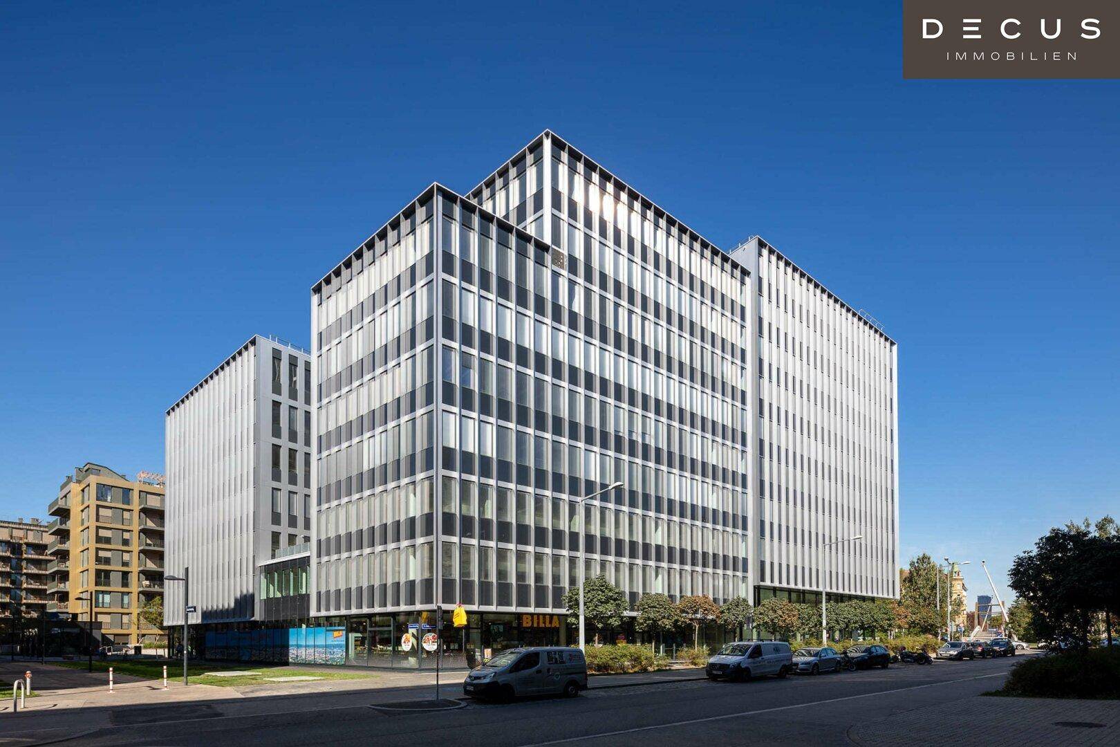 Weitläufige Ansicht eines modernen Bürokomplexes mit Glasfassade und umliegender Straße.