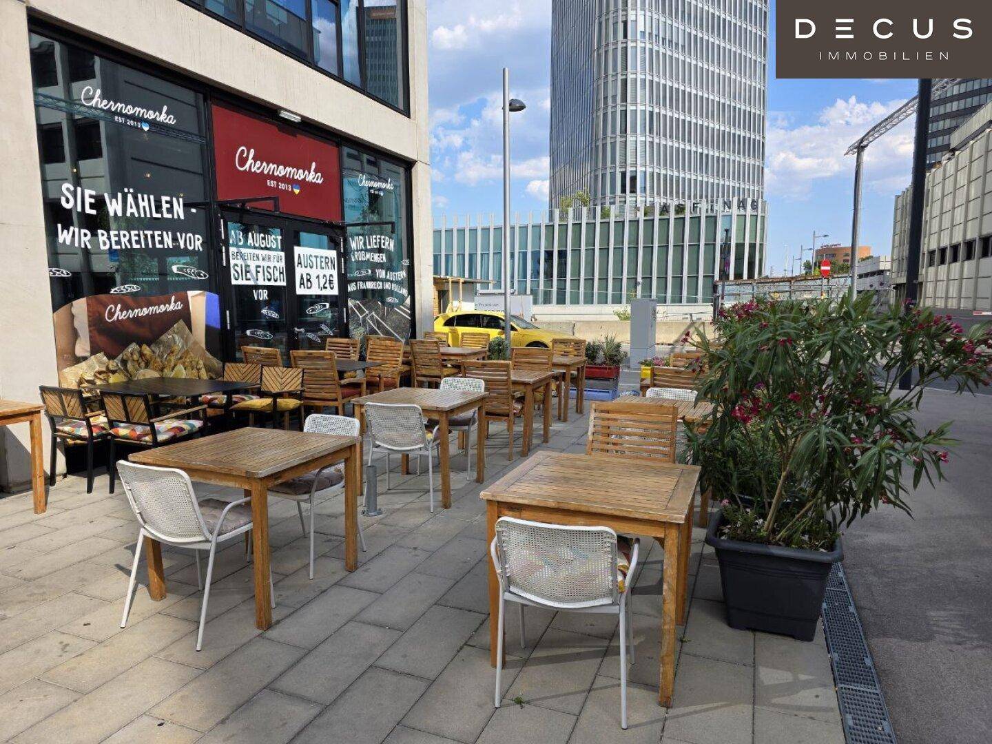 Außenbereich des Restaurants mit Holztischen und Stühlen für Gäste unter freiem Himmel.
