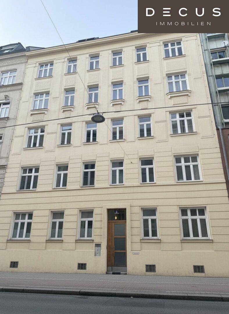 Klassische Fassade eines Mehrfamilienhauses in der Stadt mit vielen Fenstern und traditioneller Architektur.