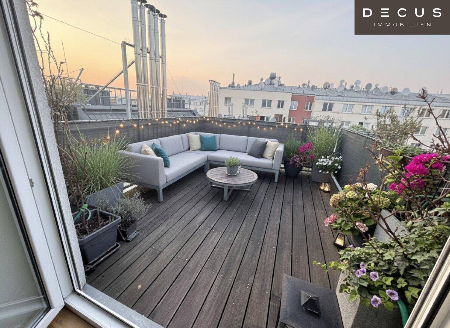 Geräumige Dachterrasse mit moderner Lounge-Sitzgruppe, Pflanzen und Stadtblick bei Sonnenuntergang.